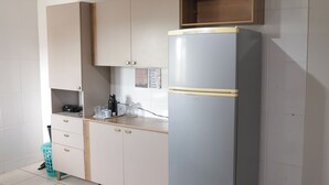 A kitchen with a refrigerator, cabinets, and a countertop.