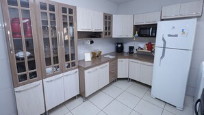 Cozinha com armários de madeira, micro-ondas, cafeteira e geladeira.