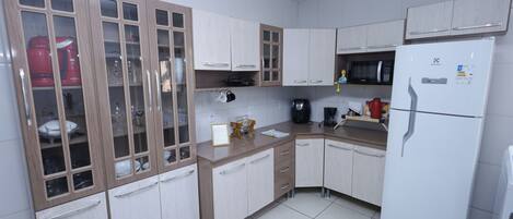 A kitchen with wooden cabinets, a microwave, a coffee maker, and a refrigerator.
