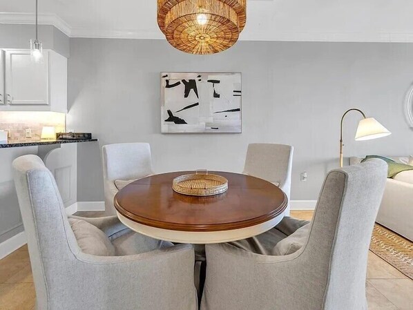 Comedor con una mesa redonda, cuatro sillas, una lámpara de fibra y una obra de arte abstracta en la pared.