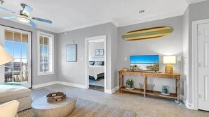 Un salón amplio con ventilador de techo, un ventanal grande y decoración temática de playa.