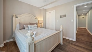A bedroom with a bed, a ceiling fan, a door, and a hallway. - 4-bedroom oceanfront condo in Sandbridge Beach with OCEAN and BAY views (Virginia Beach)