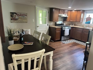 A kitchen with wooden cabinets, a stove, and a dining table with chairs.