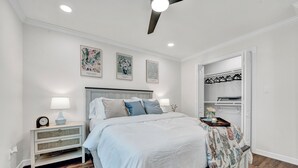 Une chambre à coucher comprenant un lit, une table de chevet et un placard avec une tringle pour suspendre les vêtements.
