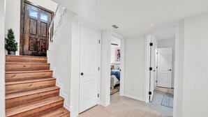 Un escalier menant à une chambre dont la porte est en bois et où se trouve une petite plante en pot.