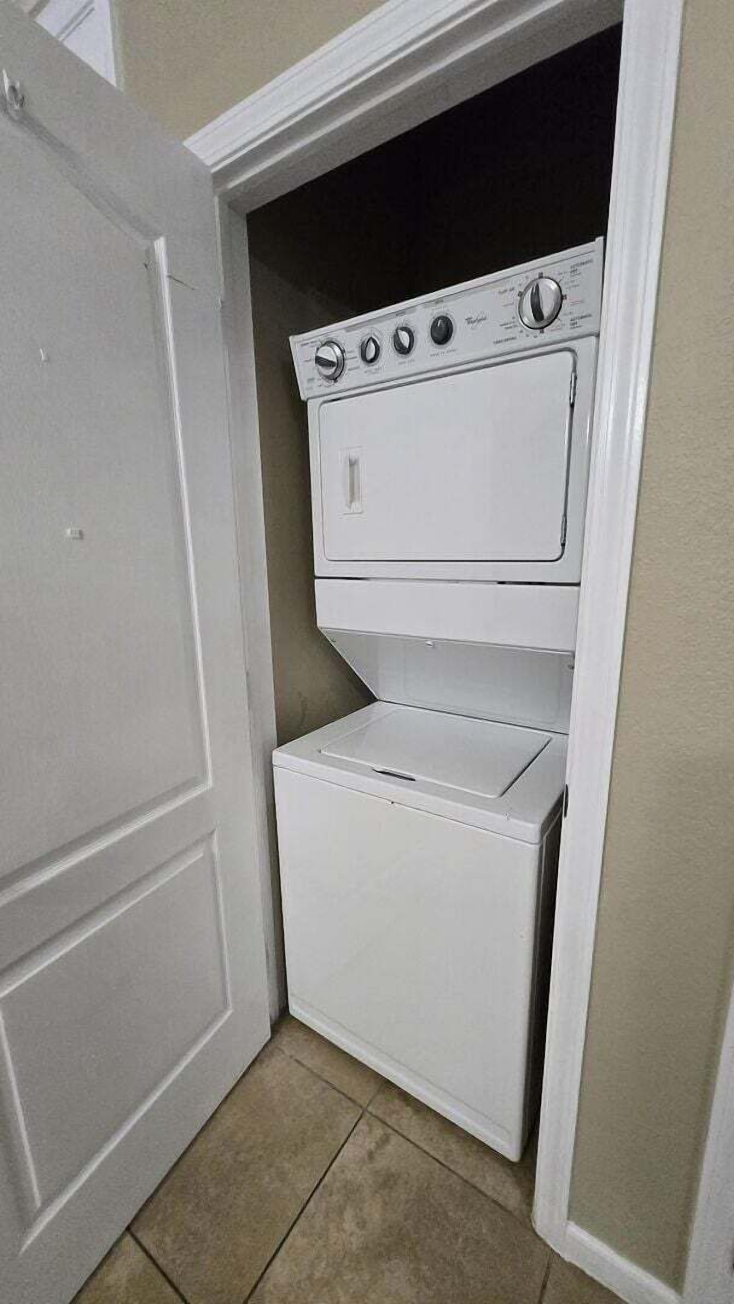 Un cuarto de lavandería con lavadora y secadora apiladas.