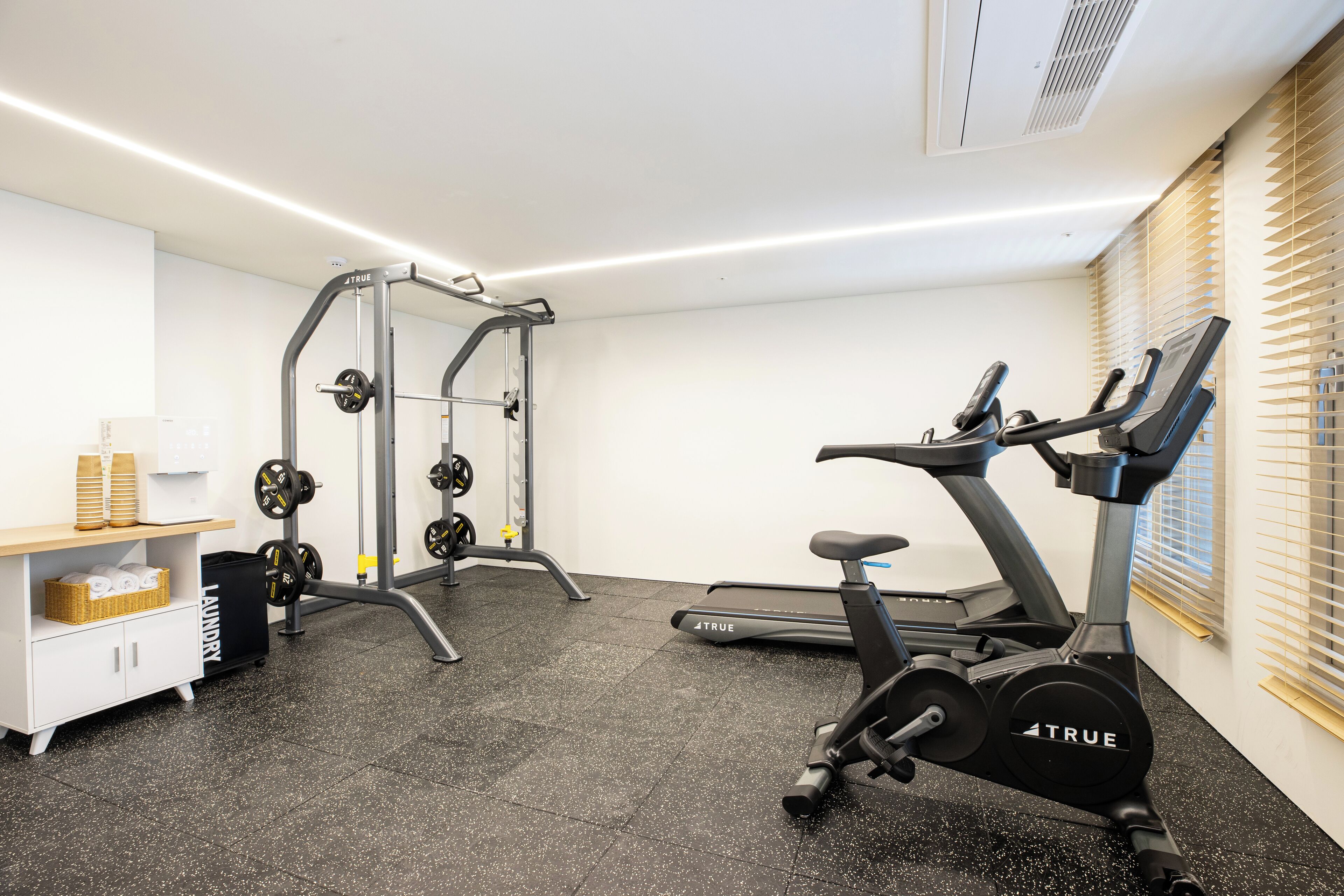 Ein Fitnessstudio mit Laufband, Hantelbank und Kurzhanteln.