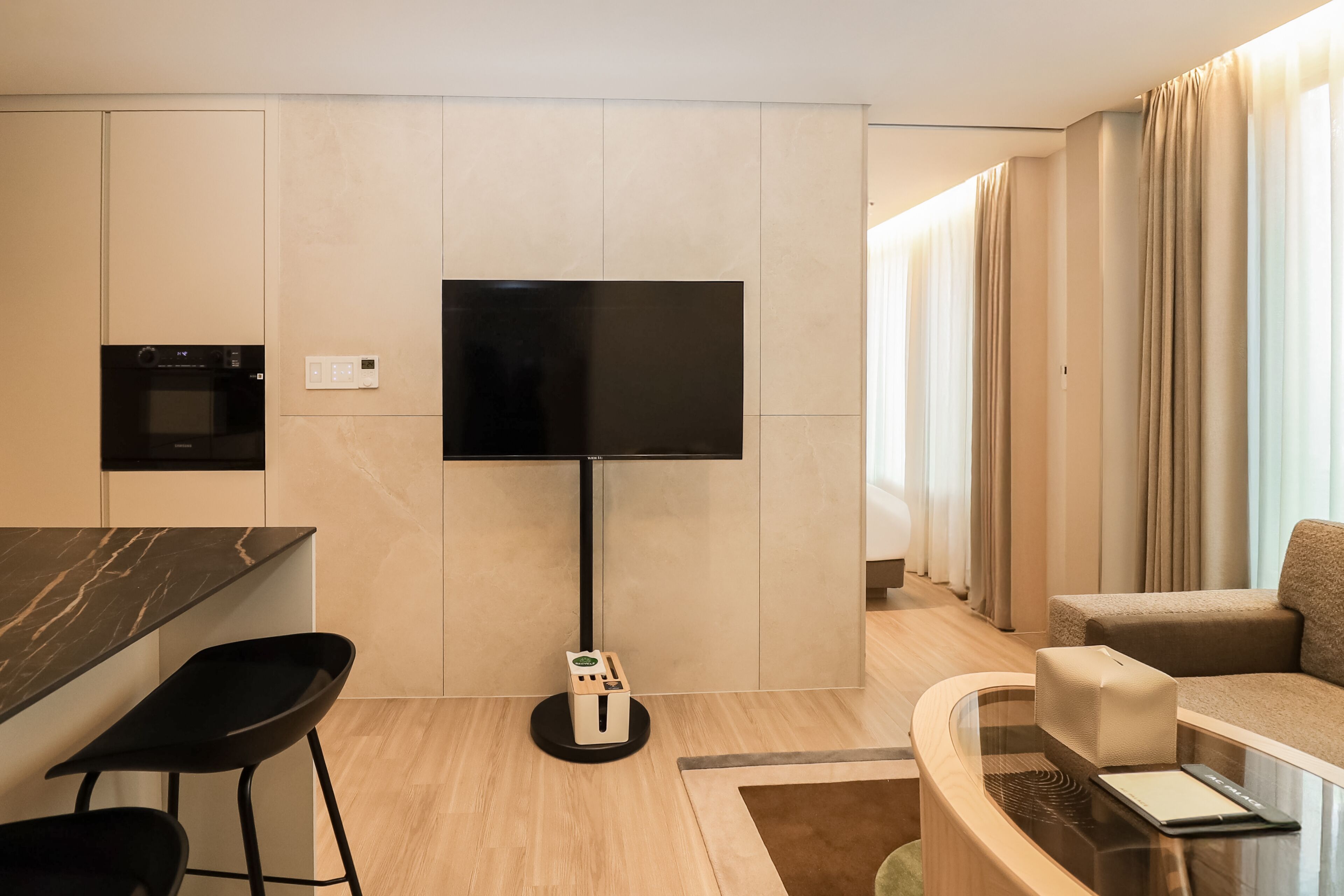 Una sala de estar moderna con un televisor de pantalla plana, un sofá, una mesa de centro y una zona de cocina con microondas.