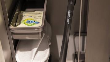 A compact bathroom with a toilet, a trash bin, and a shoehorn.