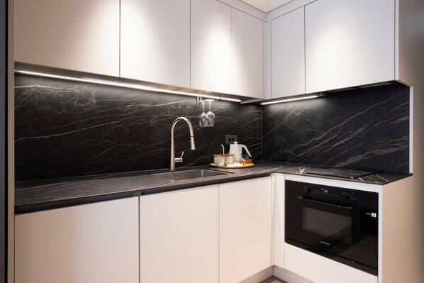 A modern kitchen with a black marble backsplash, stainless steel sink, and a built-in oven.