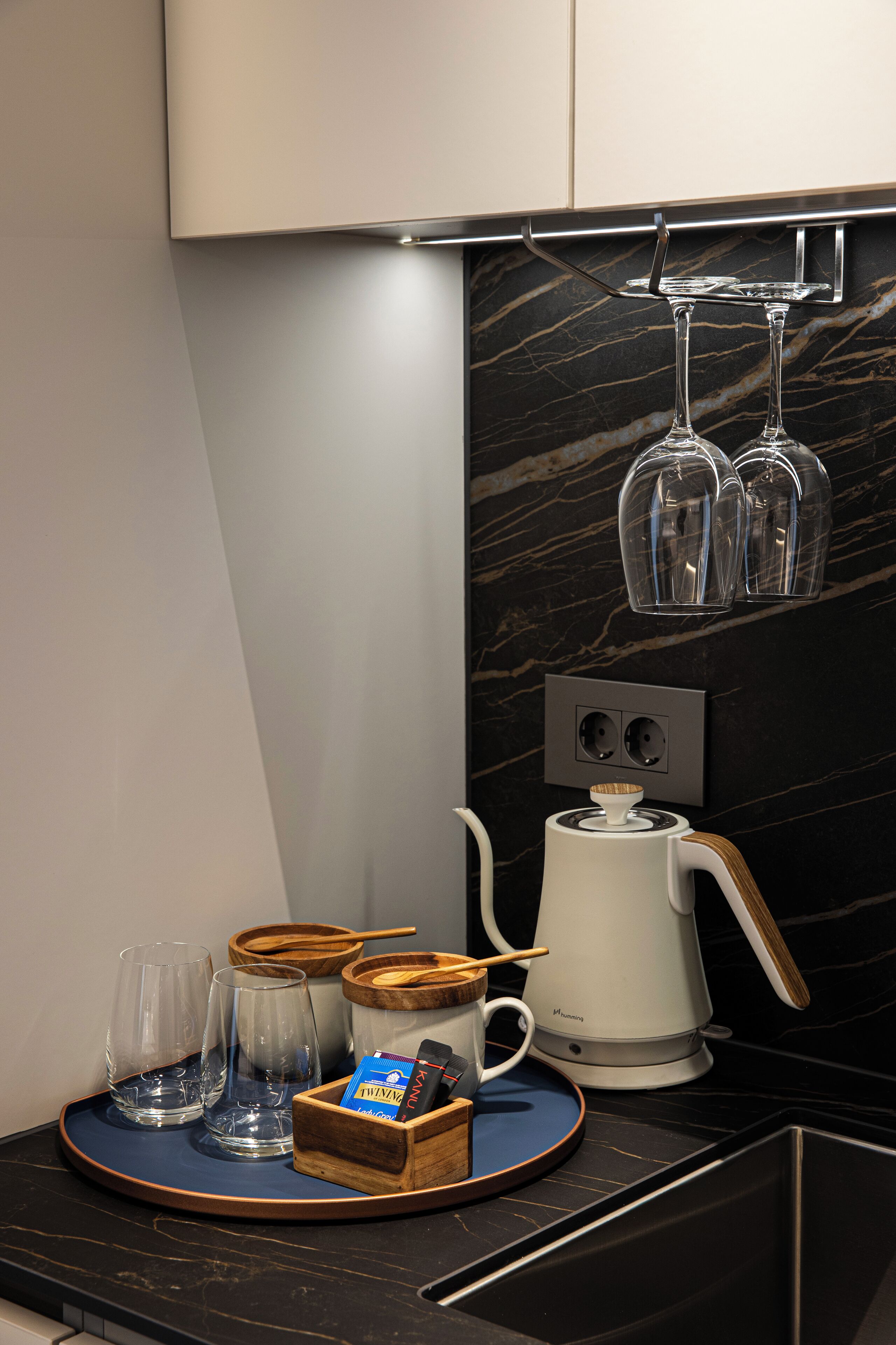 A modern kitchen with a coffee maker, two glasses, and a tray.