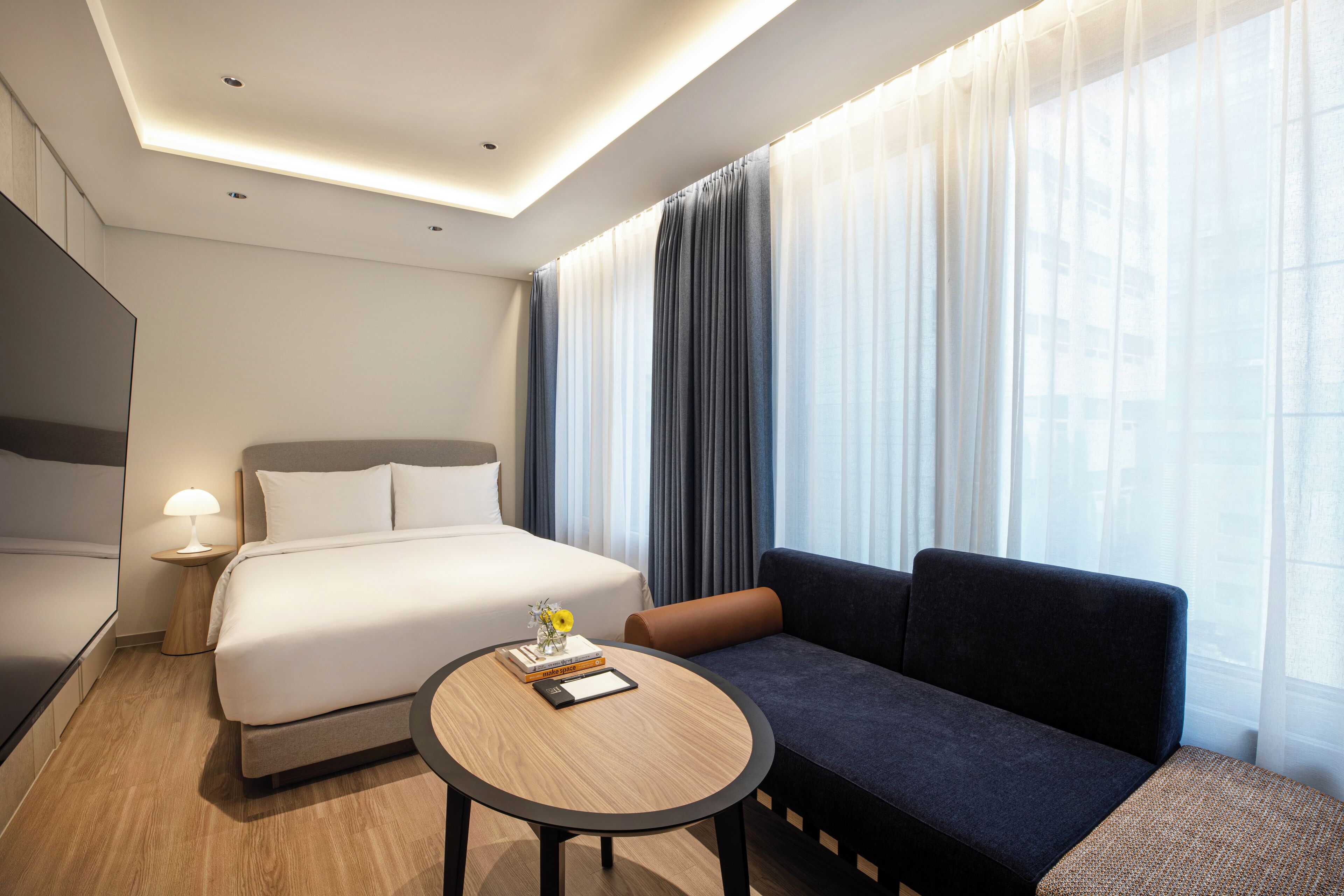Una habitación de hotel con cama, sofá, una mesita y una lámpara.