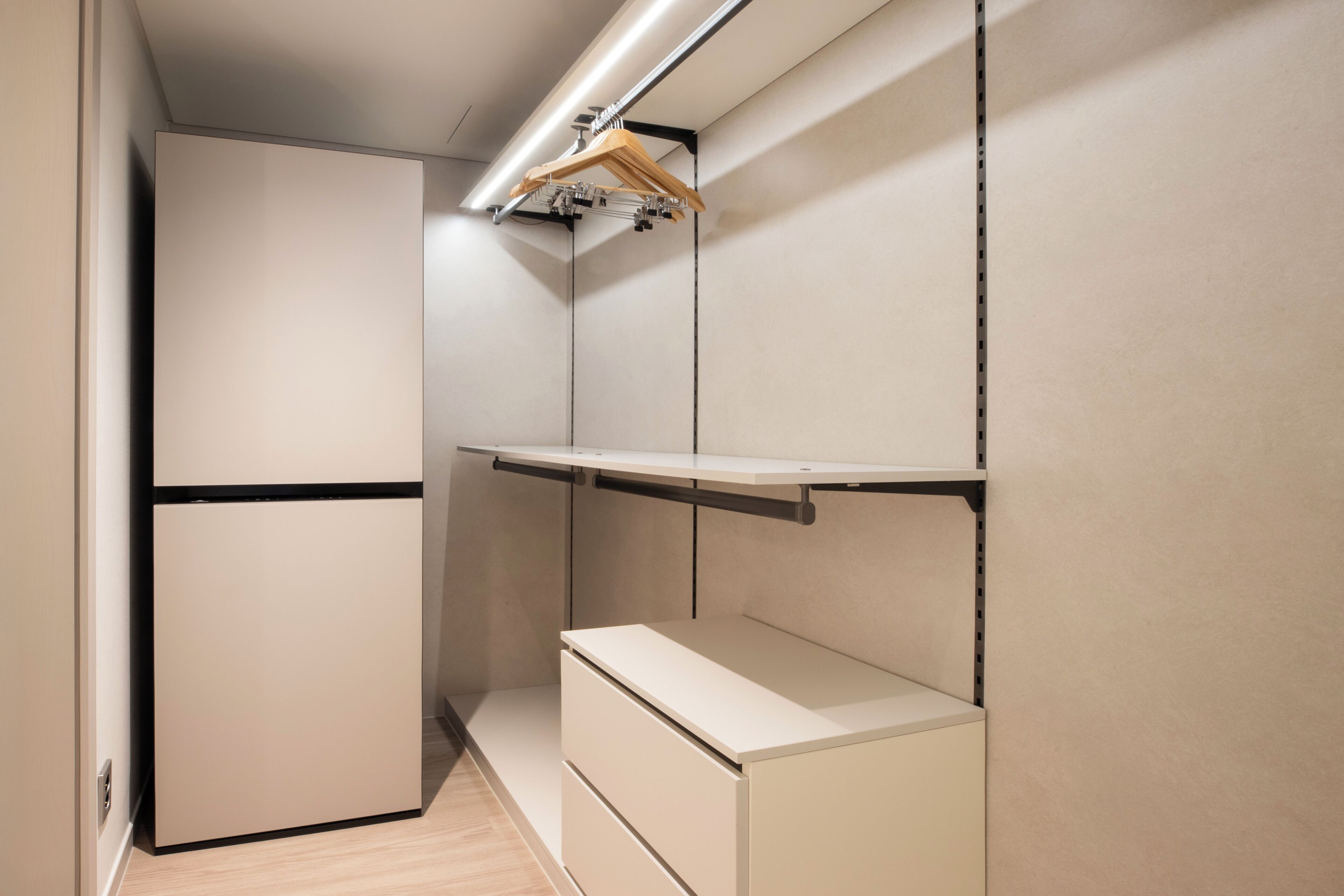 A compact, modern room with built-in storage units and a built-in refrigerator.