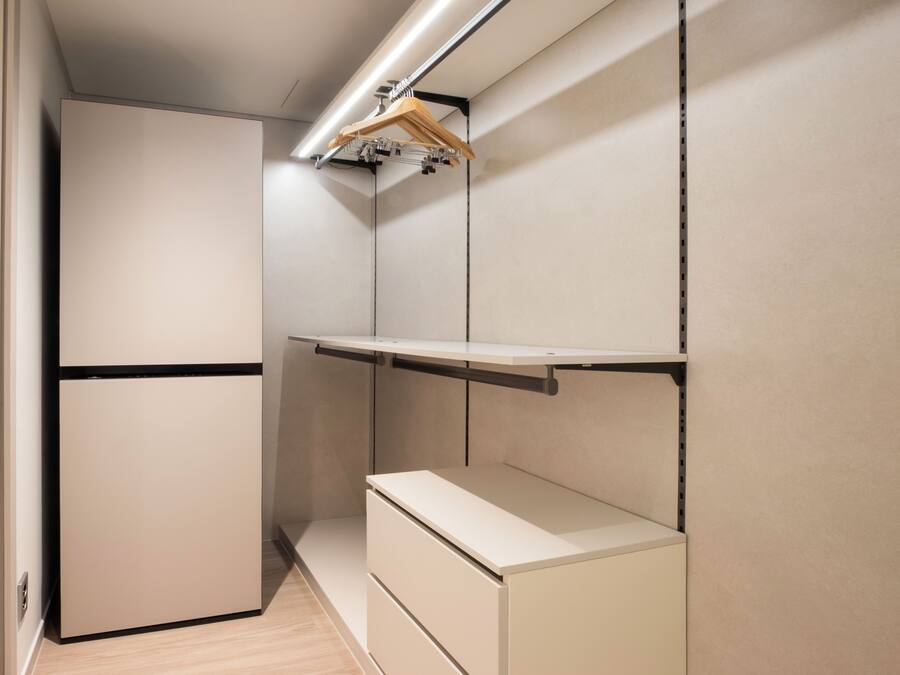 Une pièce compacte et moderne, dotée de rangements intégrés et d’un réfrigérateur encastré.