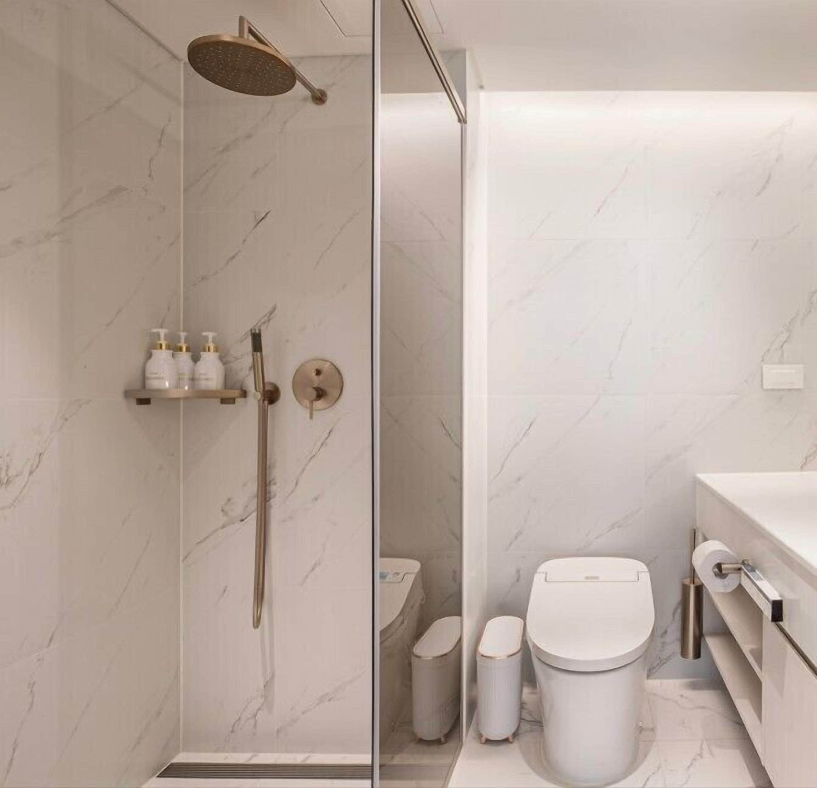 A modern bathroom with a glass shower enclosure, a toilet, and a sink.