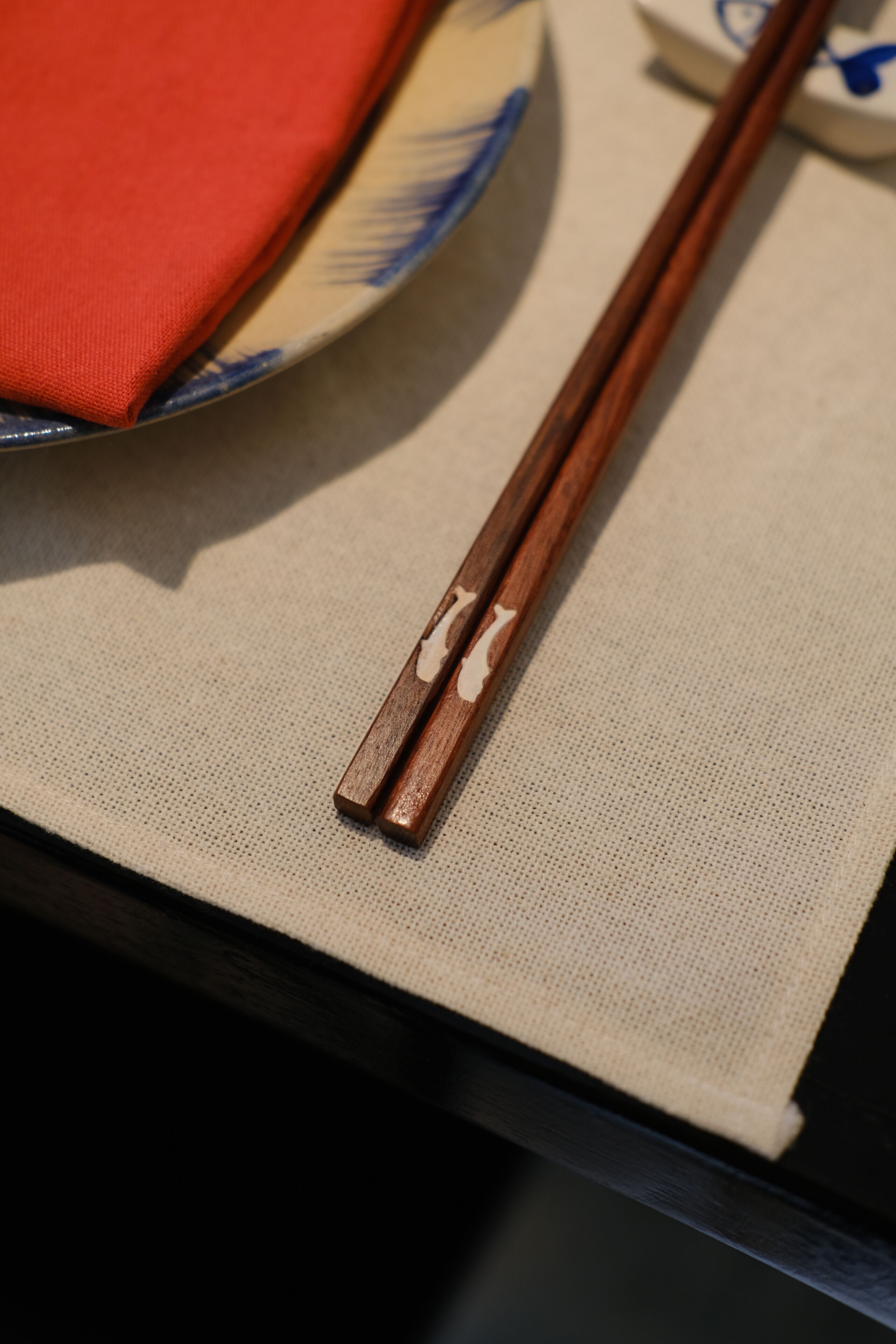 A pair of wooden chopsticks resting on a textured fabric surface.