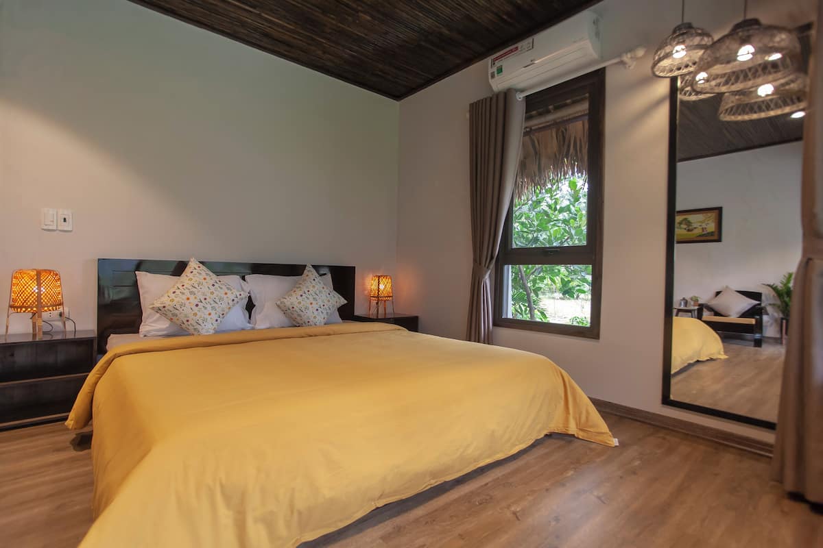 Un dormitorio con una cama grande, dos lámparas de noche, una ventana con cortinas y un espejo en la pared.