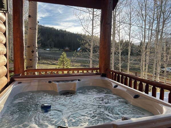 Relax in a hot tub surrounded by a serene forest view.
