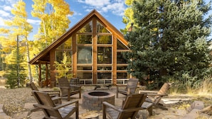 Une cabane en rondins avec un foyer et des sièges d’extérieur.