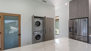 A modern kitchen with a built-in washer and dryer, stainless steel appliances, and a marble countertop. - Stylish Modern Home, Private Rooftop & City Views! (Los Angeles)