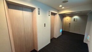 Een hotelgang met houten deuren, een vloerbedekking en een plafond met inbouwspots.