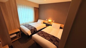 Een hotelkamer met twee bedden, een nachtkastje, een klein plankje en een raam met gordijnen.