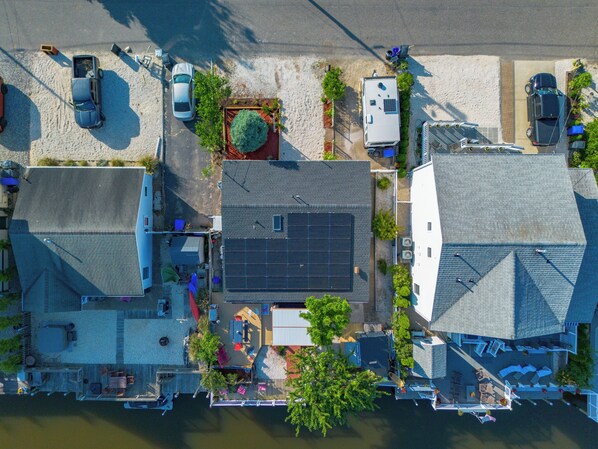 Vista aérea de una zona residencial con casas, instalación de paneles solares y un muelle junto al agua.