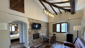 A spacious living area with a stone fireplace, a leather sofa, and a dining table with chairs. - La Melera - Starlight lodging and skiing (Llanos)