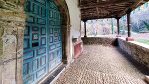 A covered walkway with a stone wall and a blue door with geometric patterns. - La Melera - Starlight lodging and skiing (Llanos)
