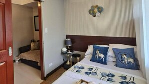 Une chambre d’hôtel comprenant un lit, un ventilateur de plafond, une table de chevet avec une lampe et un élément décoratif fixé au mur.