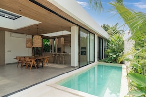 A modern house with a swimming pool, wooden dining table, and chairs. - Villa Moon by Alfred in Bali (Canggu)