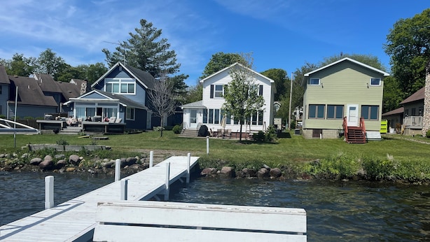 A waterfront property with a dock leading to a small body of water, surrounded by houses with various architectural styles. - Fully renovated lake front home
on Delavan’s North Shore (Delavan)