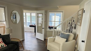A spacious living room with a dark green sofa, a white armchair, and a patterned rug. A wooden coffee table is in the center. - Fully renovated lake front home
on Delavan’s North Shore (Delavan)