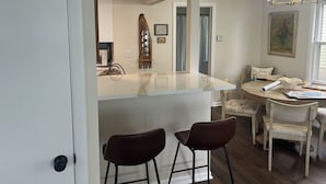 A dining area with a marble countertop, two bar stools, a round table, and a chandelier. - Fully renovated lake front home
on Delavan’s North Shore (Delavan)