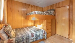 A bunk bed room with wooden walls and a door.