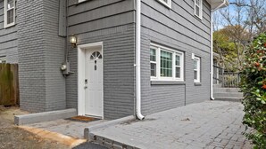 A two-story house with a grey exterior, a white door, and a small porch area.