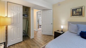 A bedroom with a bed, bedside table, lamp, and a painting on the wall.
