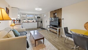 A compact living space with a kitchenette, a dining area, and a seating area with a TV and table.