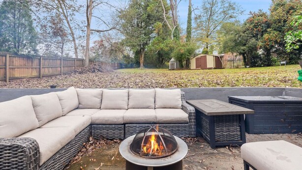 A backyard with a sectional sofa, a fire pit, and a small table.