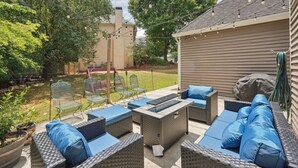 Un patio exterior con mobiliario de mimbre, una chimenea y una pérgola.