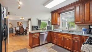 Cocina con alacenas de madera, encimeras de granito y lavavajillas.