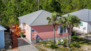 A two-story building with a red exterior, a grey roof, and a wooden deck.