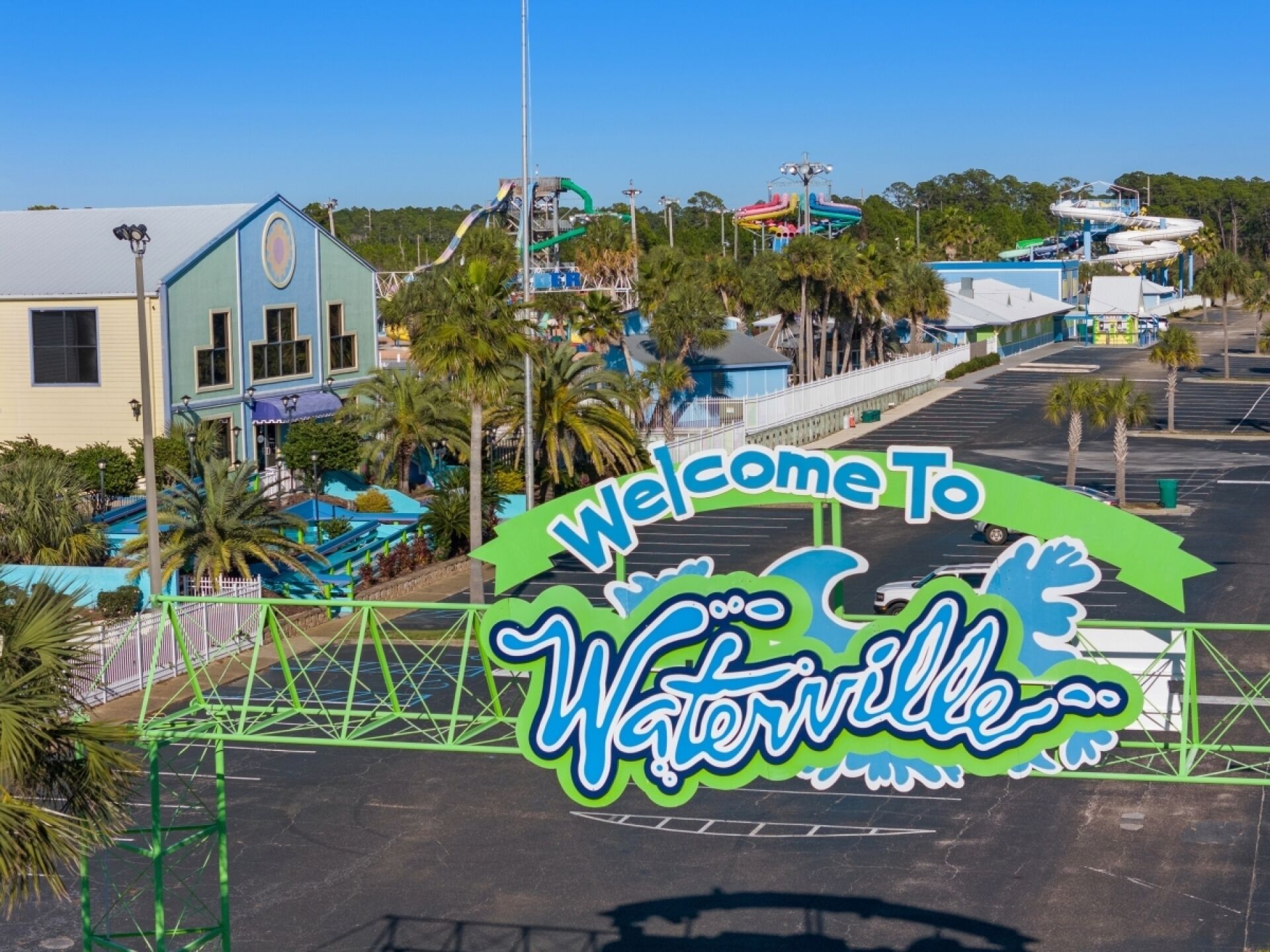 A welcome sign for Waterwell with a clear view of the surrounding area including buildings and palm trees.