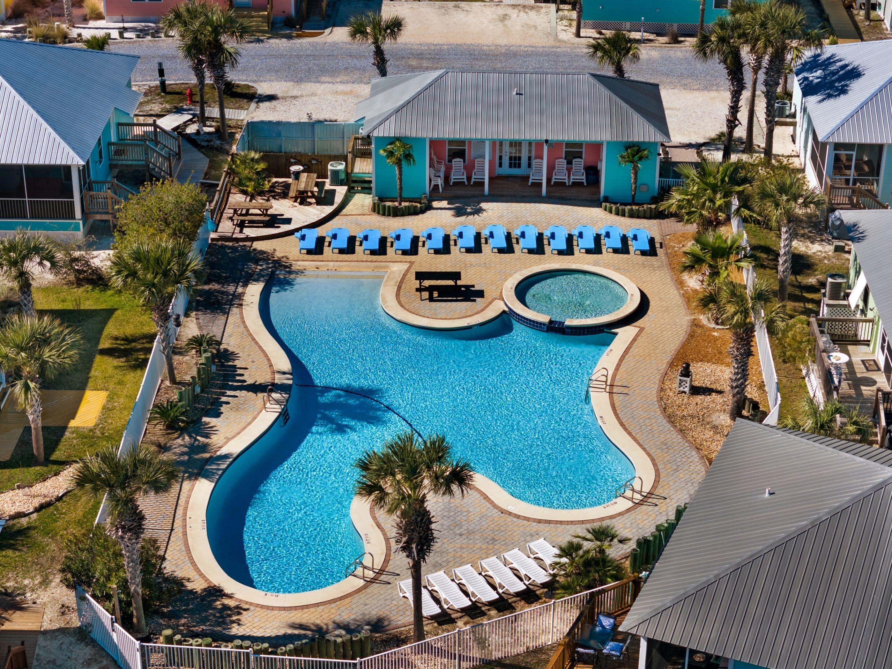 Un resort con una piscina grande, sillas de descanso y palmeras.