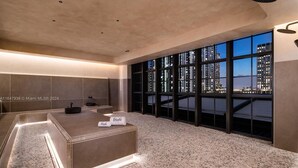 A modern hotel room with a large window, a reception desk, and a pebble-patterned floor. - 4805 - Charming Penthouse w Views & Style, Pool & Gym in vibrant Miami (Miami)