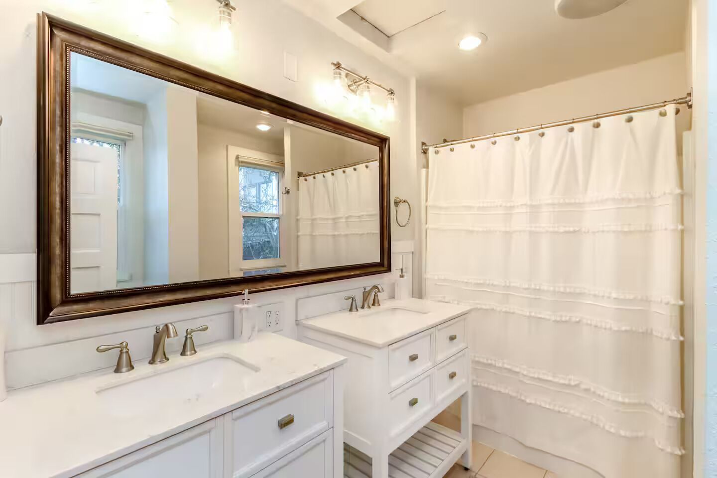 A bathroom with two sinks, a large mirror, and a shower curtain.