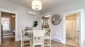 A dining area with a round table and four chairs, a ceiling light, and a mirror on the wall.