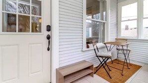 A room with a white door, a small table with chairs, and a window with blinds.