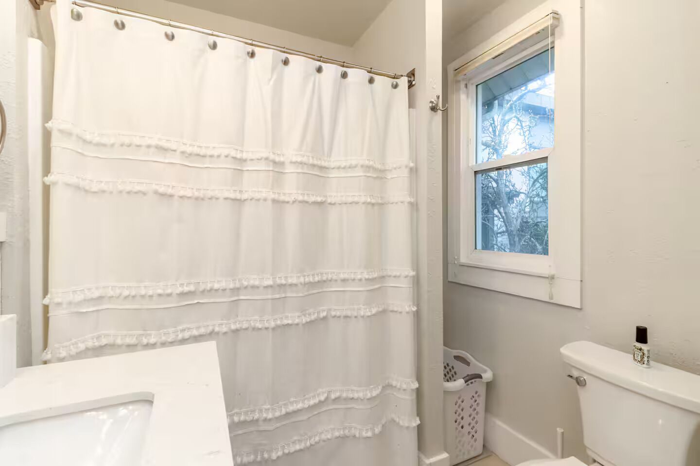 A bathroom with a white shower curtain, a window, and a toilet.