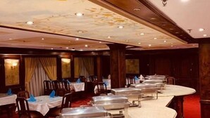 Une salle de banquet avec des tables rondes, chacune étant accompagnée d’un chariot de buffet en argent.